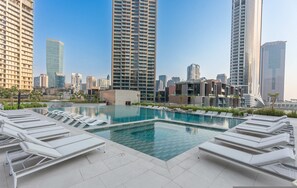 A rooftop swimming pool with lounge chairs, surrounded by high-rise buildings. - Free Housekeeping Visits During Your Stay - Stayshort - Studio in Business Bay Sleeps 2 With Burj Views (Dubai)