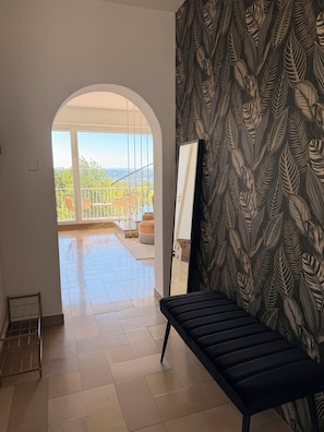 Una stanza con una grande finestra, una panca nera e un muro decorato.