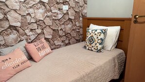 A bedroom with a stone wall, a bed with a white sheet, and two pillows with text. - Country house for relaxation!! 3 bedrooms, swimming pool, fishing lake, fully equipped kitchen. (Cambuí)