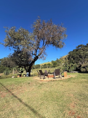 A tree-lined outdoor area with a brick fire pit and outdoor furniture. - Country house for relaxation!! 3 bedrooms, swimming pool, fishing lake, fully equipped kitchen. (Cambuí)
