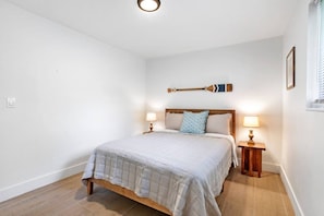 A bedroom with a bed, two bedside tables with lamps, a wooden headboard, and a wall-mounted decoration. - 3BD/2BA Palm Gardens Retreat (Palm Beach Gardens)