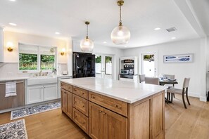 A spacious kitchen with a large island, wooden cabinets, and pendant lighting. - 3BD/2BA Palm Gardens Retreat (Palm Beach Gardens)