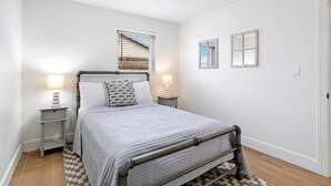 Une chambre à coucher avec un lit, des tables de chevet, une fenêtre et une porte.