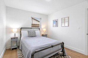 A bedroom with a bed, bedside tables, a window, and a door. - 3BD/2BA Palm Gardens Retreat (Palm Beach Gardens)