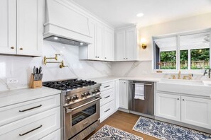 A modern kitchen with white cabinetry, a stainless steel stove, and a built-in oven. - 3BD/2BA Palm Gardens Retreat (Palm Beach Gardens)