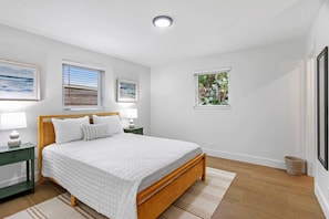 A bedroom with a bed, two bedside tables, a window, and a framed picture on the wall. - 3BD/2BA Palm Gardens Retreat (Palm Beach Gardens)