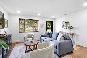 A living room with a grey sofa, two armchairs, a wooden coffee table, and a small side table with a vase. - 3BD/2BA Palm Gardens Retreat (Palm Beach Gardens)