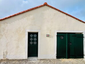 Un bâtiment à la façade beige, à la porte verte et au toit recouvert de tuiles rouges.