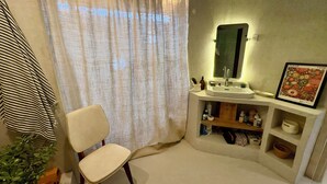 Un bagno con un lavandino bianco, uno specchio, un quadro incorniciato e una sedia.