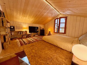 A cozy room with a bed, a television, a bookshelf, and a window. - Country house with a large garden – 10 minutes from the beaches and 5 minutes from O'Fun Park (Avrillé)