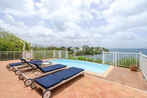 A pool area with lounge chairs and a view of the sea. - Villa Grand Large - Four Bedroom Villa, Sleeps 8 (Les Trois-Îlets)