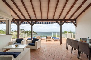 A covered patio with outdoor furniture, a view of the sea, and a tiled floor. - Villa Grand Large - Four Bedroom Villa, Sleeps 8 (Les Trois-Îlets)