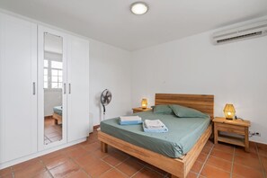 Ein Schlafzimmer mit einem Bett, einem Kleiderschrank, einem Ventilator und zwei Nachttischlampen.