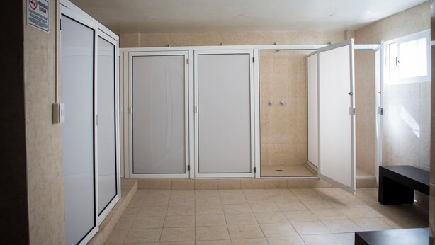 A hallway with three doors, a bench, and a sign prohibiting smoking. - Casa Local Mestizo Hostal (Mexico City)