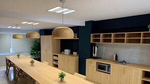 A modern kitchen with wooden cabinets, a built-in microwave, and a long dining table with chairs. - Casa Local Mestizo Hostal (Mexico City)