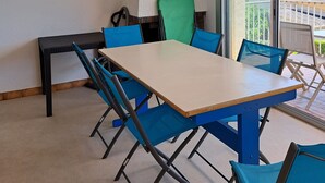 Ein Zimmer mit Tisch, Stühlen, Deckenventilator, Fenster und einem Bild an der Wand.