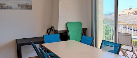 A room with a table and chairs, a ceiling fan, a window, and a painting on the wall.