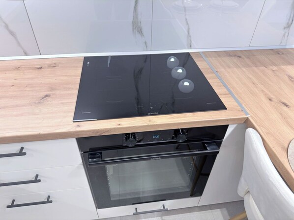A kitchen with a black stove top oven, a built-in oven, and wooden countertops. - Stylish City 2BR Apartment | Ad Residences (Thessaloniki)