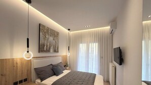Un dormitorio moderno con una cama, mesitas de noche, un televisor montado en la pared y un cuadro.