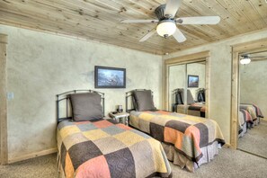 A room with two beds, a ceiling fan, a framed picture on the wall, and a mirror reflecting the room. - Bear Creek TWO by Notable Vacation Rentals (Estes Park)