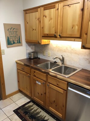 Una cocina con armarios de madera, un lavamanos de acero inoxidable y un tostador.