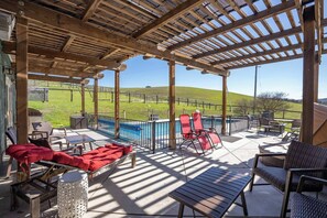 Une terrasse extérieure dotée d’une piscine, de chaises longues et d’une pergola.