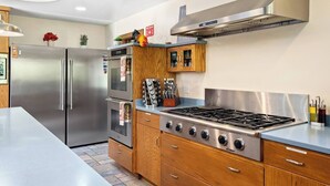 A modern kitchen with stainless steel appliances, wooden cabinets, and a gas stove. - Harvest Ridge Ranch 5 Bedroom Farmhouse Sleeps 14 (Paso Robles)