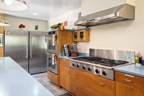 Une cuisine moderne dotée d’appareils électroménagers en acier inoxydable, de meubles en bois et d’une cuisinière à gaz.