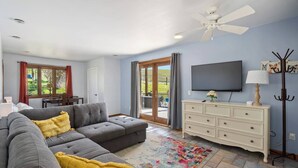 A living room with a grey sectional sofa, a white dresser, a flat-screen TV, and a ceiling fan. - Harvest Ridge Ranch 5 Bedroom Farmhouse Sleeps 14 (Paso Robles)