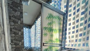 Un baño con inodoro, ducha con puerta de cristal y pared de piedra.