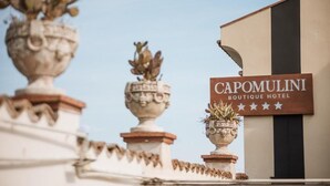 A hotel sign with the name 'Capomulini Boutique Hotel' and decorative pots on the roof. - Capomulini Boutique Hotel (Capo Mulini)