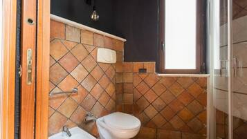 A bathroom with a white toilet, a sink, and a shower area.
