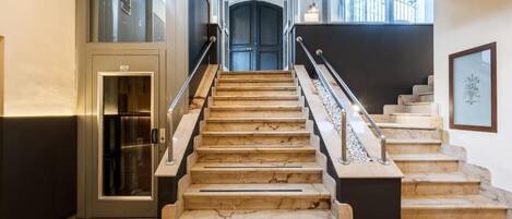 Una escalera de mármol con barandales de metal que lleva a una puerta.