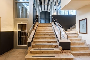 A staircase with marble steps and metal railings leading to a door.