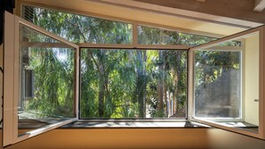 A room with a large, open window revealing a dense, green forest view. - Capomulini Boutique Hotel (Capo Mulini)