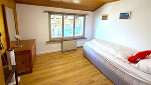 Une pièce avec un lit, un bureau, une fenêtre et un radiateur.
