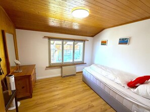 Um quarto com cama, escrivaninha, janela e radiador.