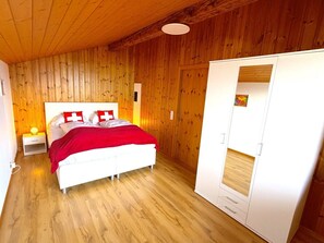 Une pièce avec un lit, une armoire, des murs en bois et un plancher en bois.