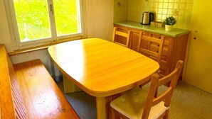 Une cuisine de taille réduite avec une table et des chaises en bois, une fenêtre offrant une belle vue et un mur recouvert de carreaux.