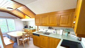 Une cuisine compacte avec des meubles en bois, un lave-vaisselle encastré et un coin repas comprenant une table et des chaises.