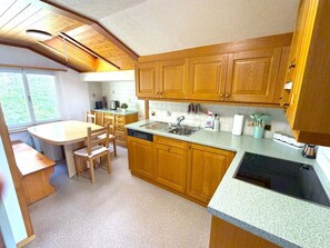 Eine kompakte Küche mit Holzausbau, einem integrierten Geschirrspüler und einem Essbereich mit Tisch und Stühlen.