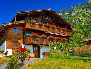 Ein traditionelles Holzchalet mit mehreren Balkonen, einer Haustür und einer kleinen Veranda.