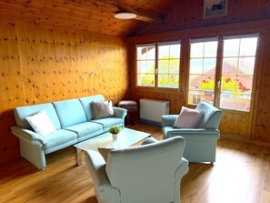 Ein Zimmer mit einem hellblauen Sofagarnitur, einem kleinen Tisch mit einer Pflanze und einer Heizung.