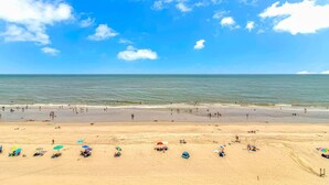 A beach with people and umbrellas, a clear sky, and calm sea. - Sea Mist 20509 Direct Ocean Front Condo (Myrtle Beach)