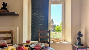 Un tavolo da pranzo con frutta, bicchieri e vista su un edificio attraverso una finestra.