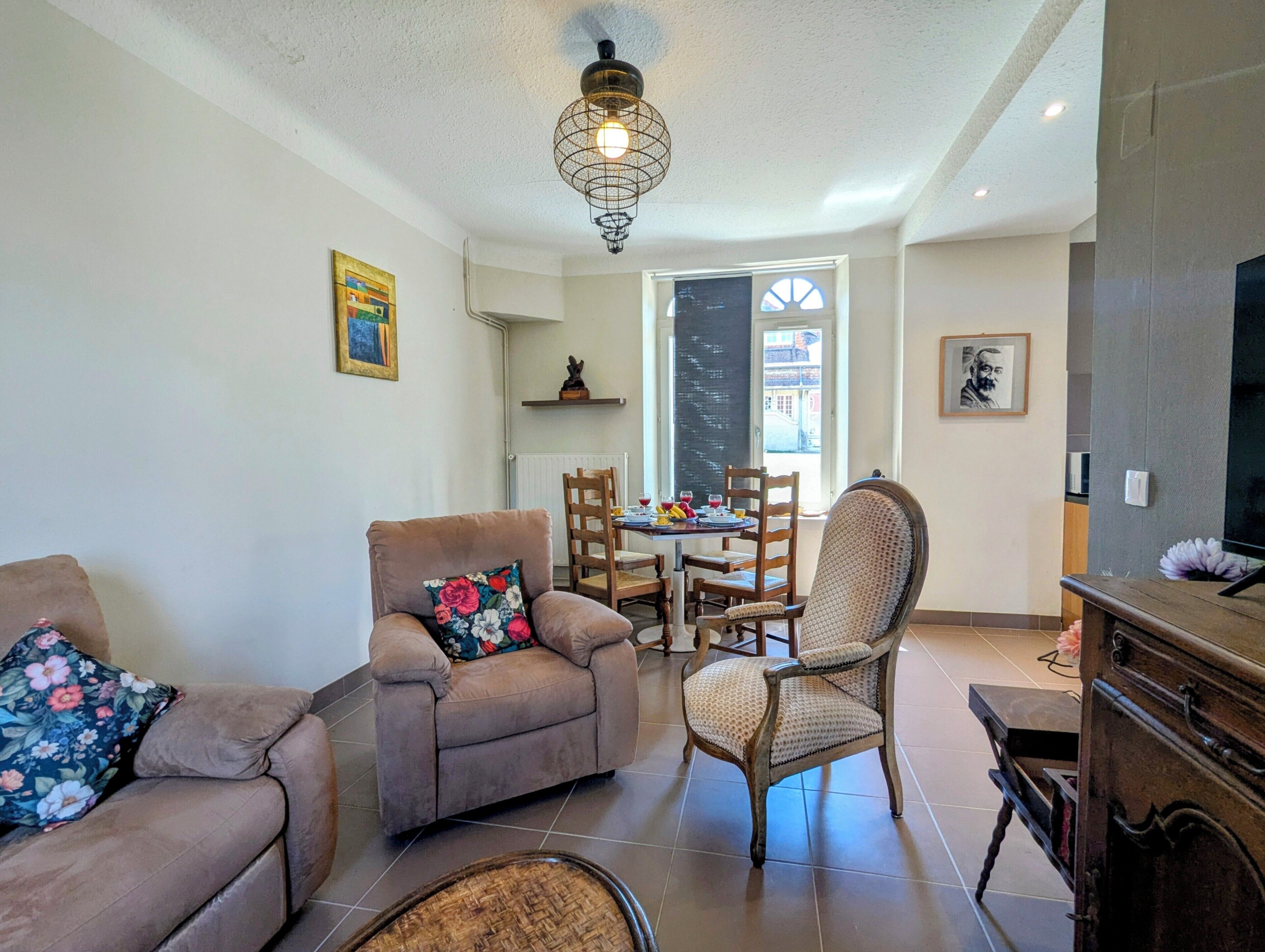 Un salon comprenant un canapé, un fauteuil et une table à manger avec des chaises.