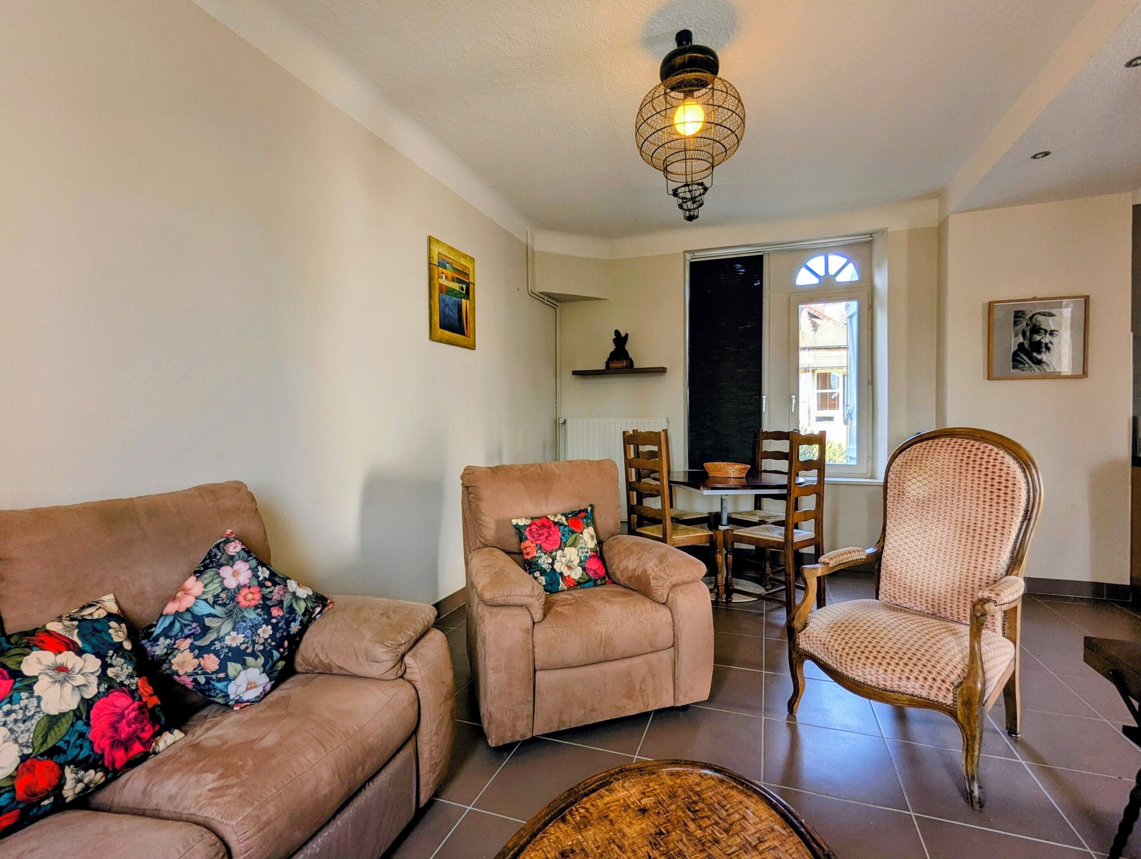 A living room with a sofa, armchair, and a dining table with chairs.
