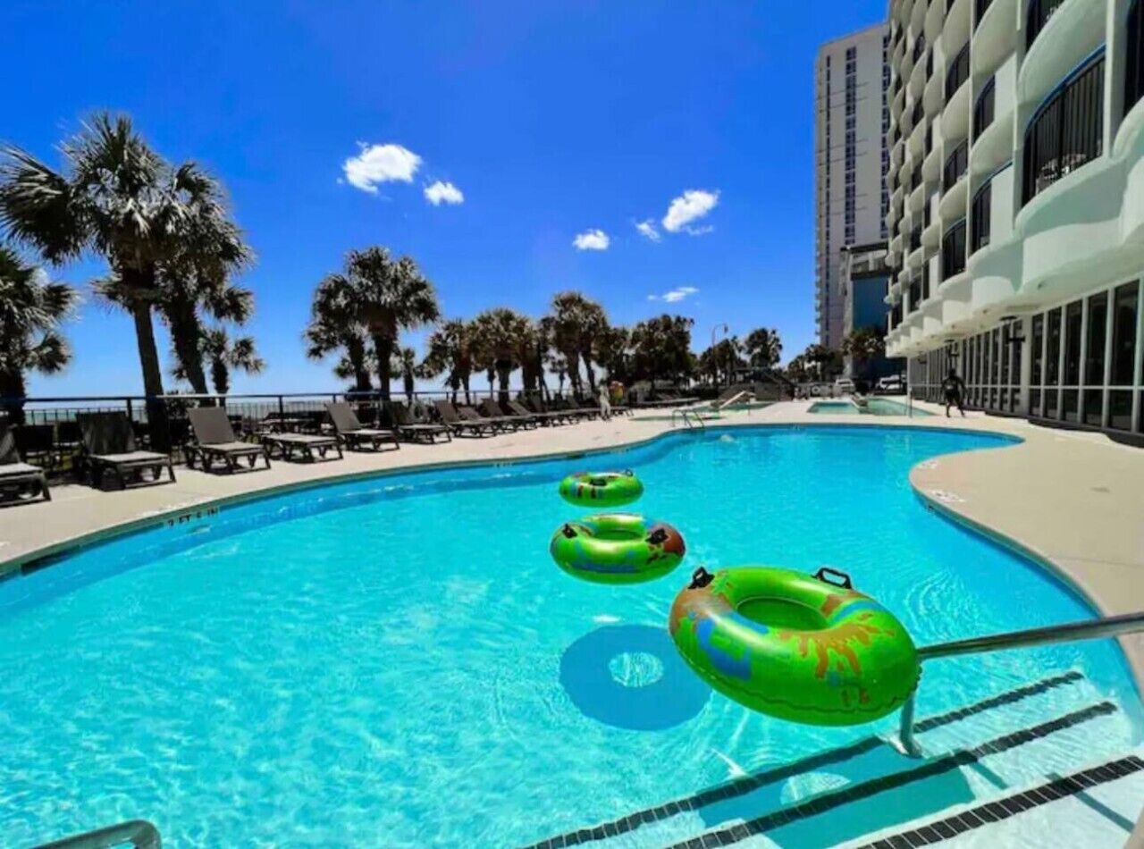 A swimming pool with lounge chairs and palm trees.