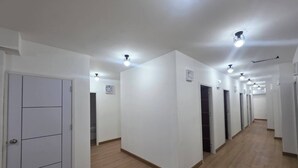 A corridor with white walls, wooden flooring, and multiple doors. - Hotel Backpack   BTS Punnawithi PKK2 (Bangkok)