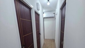 A narrow hallway with wooden flooring and white walls, leading to closed doors. - Hotel Backpack   BTS Punnawithi PKK2 (Bangkok)